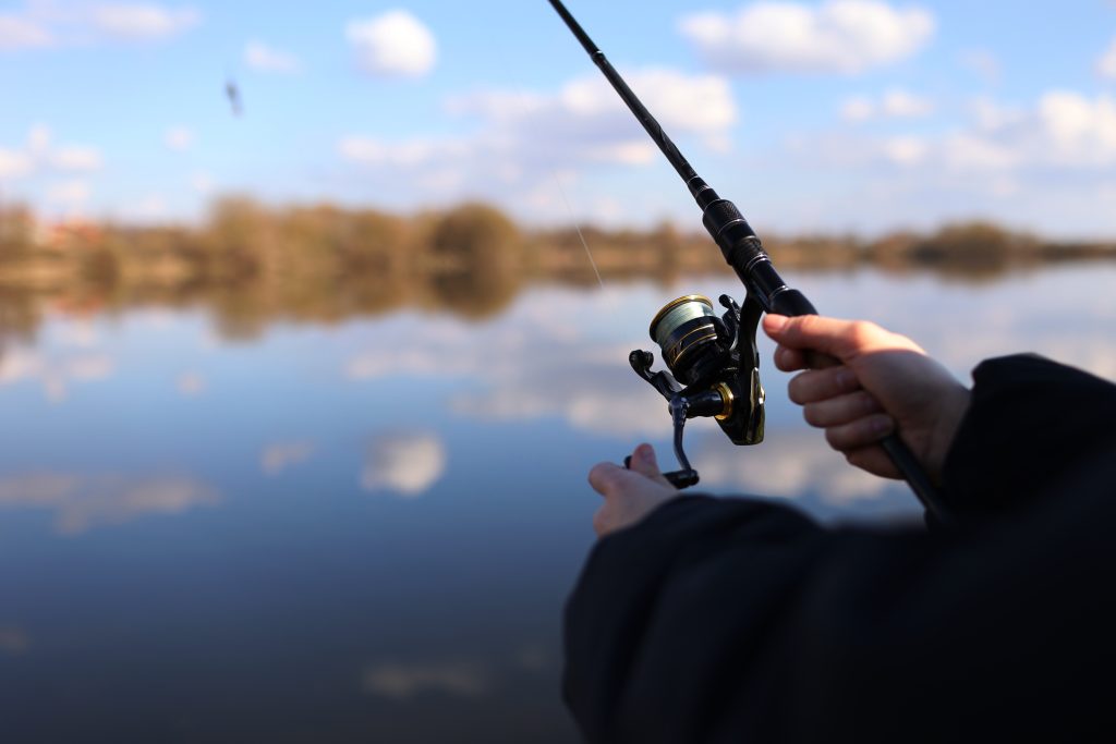 Man,Catching,Fish,,Pulling,Rod,While,Fishing,From,Lake,Or